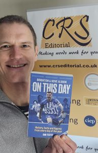 Craig Smith of CRS Editorial with Dan Tester's new book, Brighton & Hove Albion On This Day. A CRS Editorial roller banner is in the background.